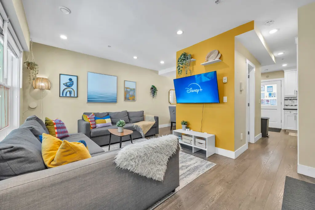 Settle into this vibrant living room featuring plush seating, warm lighting, and entertainment at your fingertips — the perfect spot to unwind after a day exploring Vancouver.