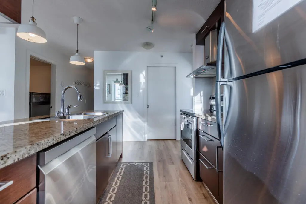 A sleek, full kitchen with stainless steel appliances and stone countertops offers a clean, functional space for everyday cooking. Thoughtfully laid out for comfort and ease, it’s ideal for settling into a longer Vancouver stay.