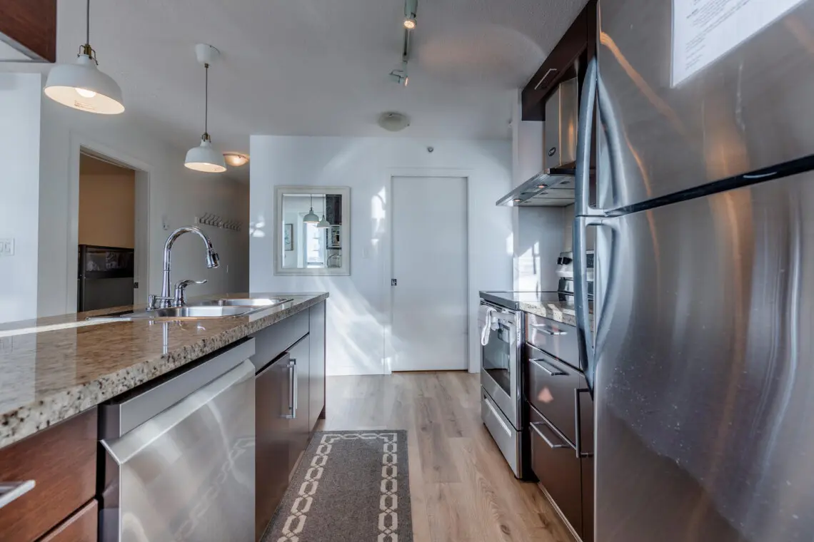 A sleek, full kitchen with stainless steel appliances and stone countertops offers a clean, functional space for everyday cooking. Thoughtfully laid out for comfort and ease, it’s ideal for settling into a longer Vancouver stay.