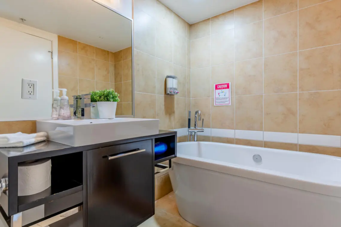 The primary ensuite bathroom offers a touch of spa-like luxury with its sleek standalone tub — perfect for a relaxing soak after a full day in the city. Warm tones and modern finishes create a calming retreat within this stylish Vancouver stay.