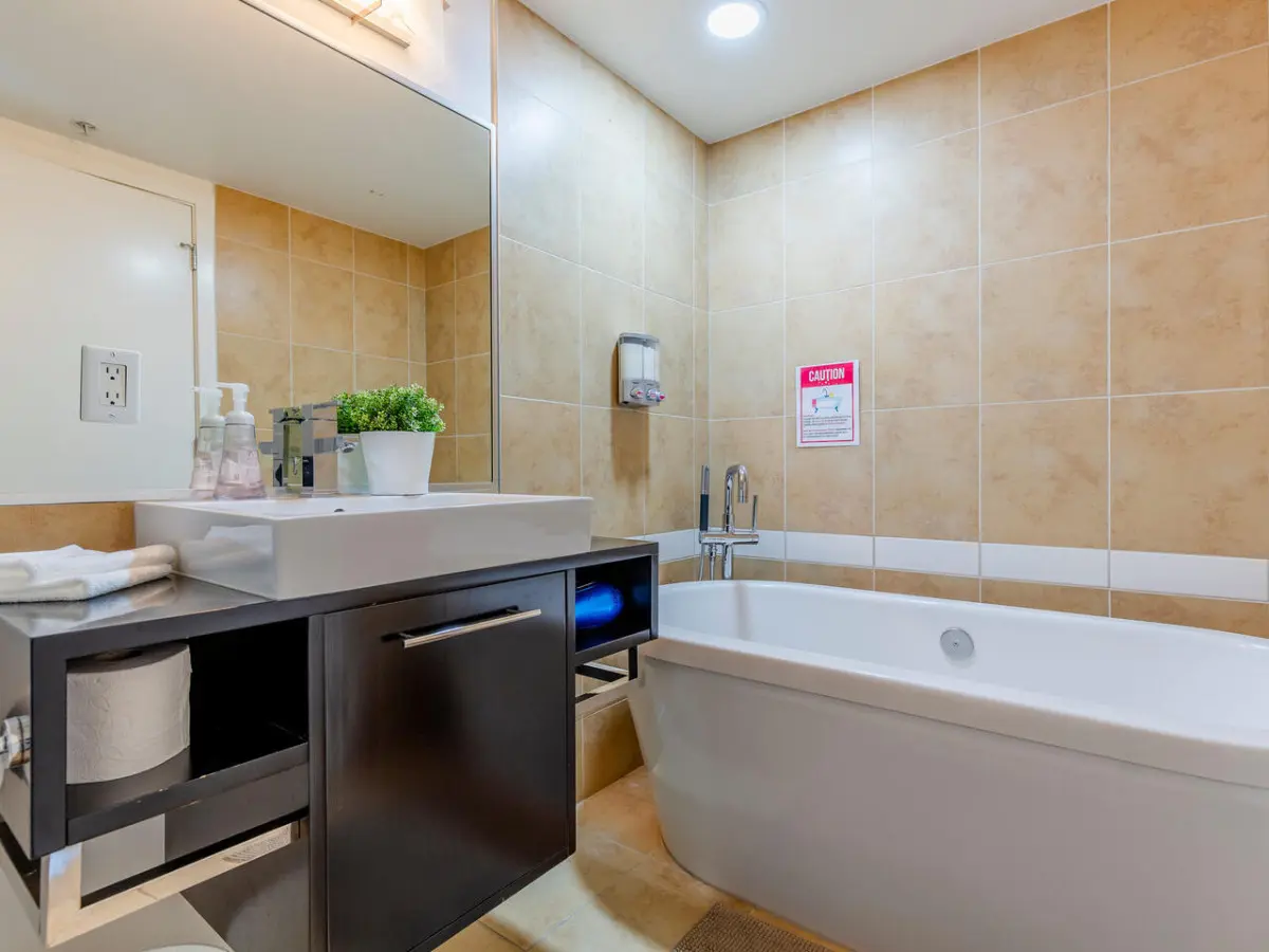 The primary ensuite bathroom offers a touch of spa-like luxury with its sleek standalone tub — perfect for a relaxing soak after a full day in the city. Warm tones and modern finishes create a calming retreat within this stylish Vancouver stay.