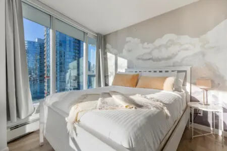 Guests can drift into relaxation in this serene bedroom, where soft tones and airy light create a true “cloud nine” experience. Floor-to-ceiling windows showcase Vancouver’s skyline, blending the calm of a cozy retreat with the beauty of an urban escape.