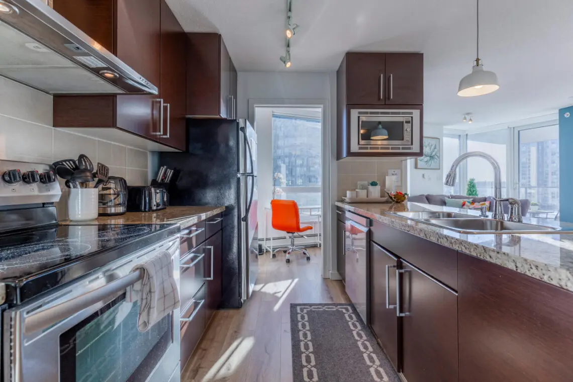 A chic culinary space where style meets functionality — this modern kitchen features stainless-steel appliances, granite countertops, and all the essentials for effortless home cooking during your Vancouver stay.