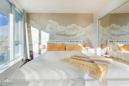 Wake up to the clouds — literally. This serene bedroom combines soft tones, dreamy wall art, and panoramic city views to create the perfect space for peaceful rest and rejuvenation.