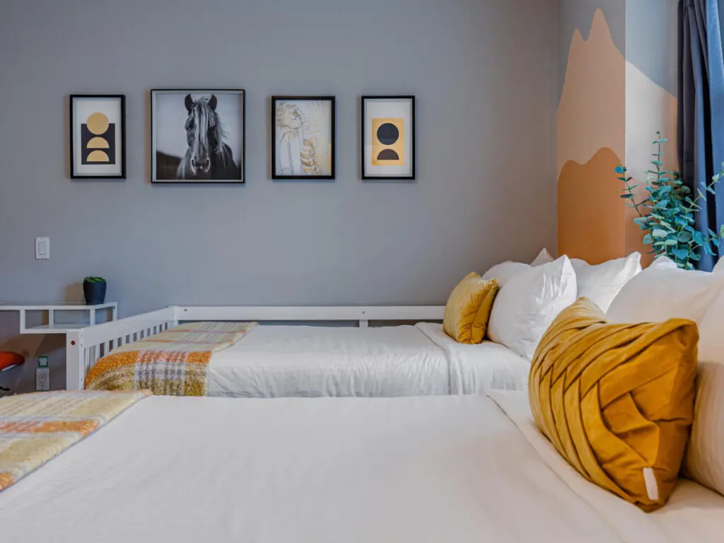 The second bedroom features two cozy double beds with soft linens and warm accents, creating a bright and restful space for families or friends to unwind after a day in Vancouver