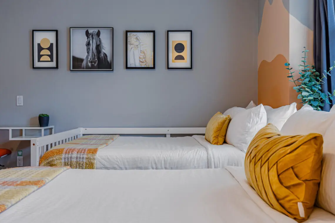 The second bedroom features two cozy double beds with soft linens and warm accents, creating a bright and restful space for families or friends to unwind after a day in Vancouver