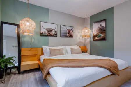 The primary bedroom features a plush king bed with soft linens and blackout blinds for a restful night’s sleep. Thoughtful details and warm lighting create a calm, inviting retreat to unwind in comfort.