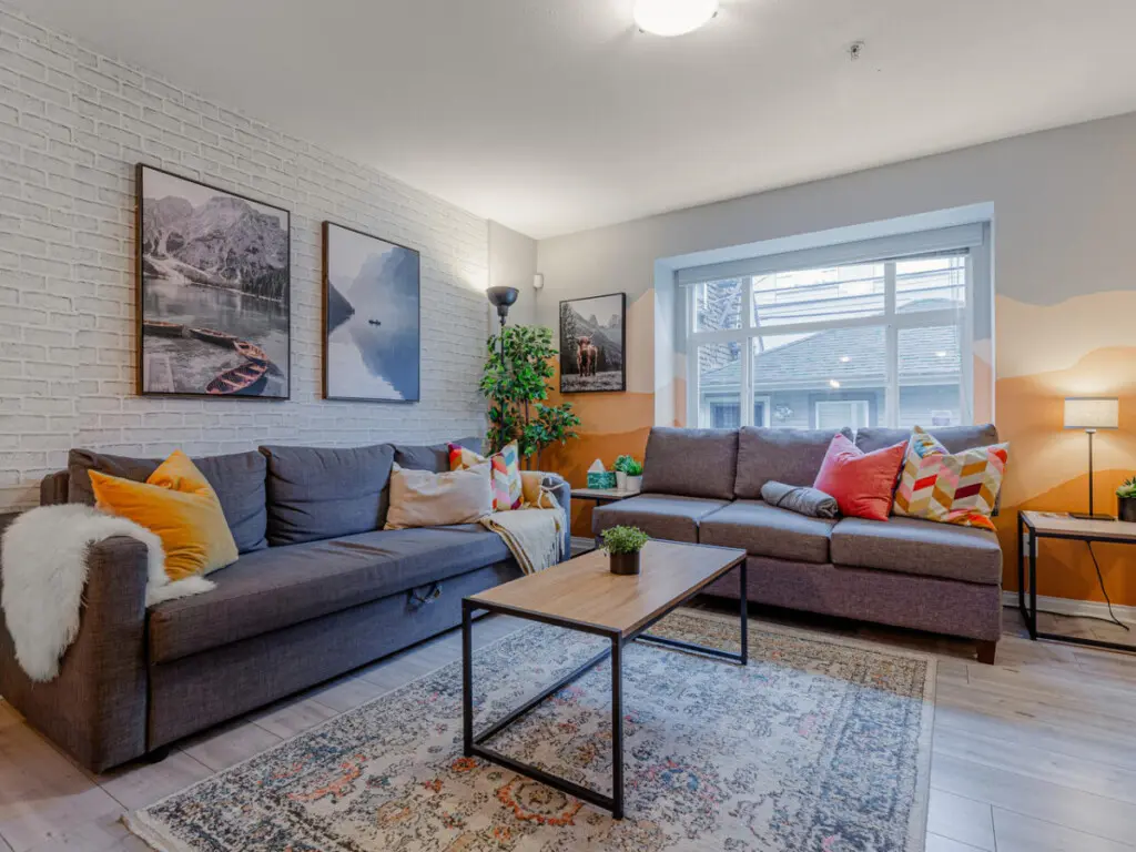 The bright, welcoming living room offers plenty of comfortable seating — perfect for relaxing, socializing, or unwinding after a day out in the city.