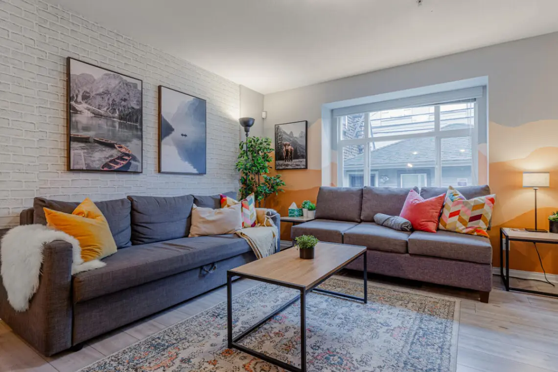 The bright, welcoming living room offers plenty of comfortable seating — perfect for relaxing, socializing, or unwinding after a day out in the city.