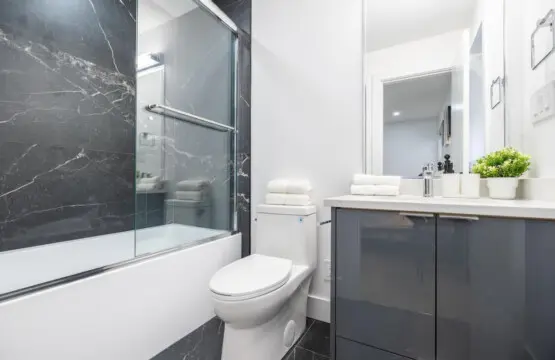 Connected to the main-floor bedroom, this private ensuite features dark marble-inspired tiles, a glass-enclosed bathtub, and a modern vanity — offering guests a stylish and comfortable space to unwind.