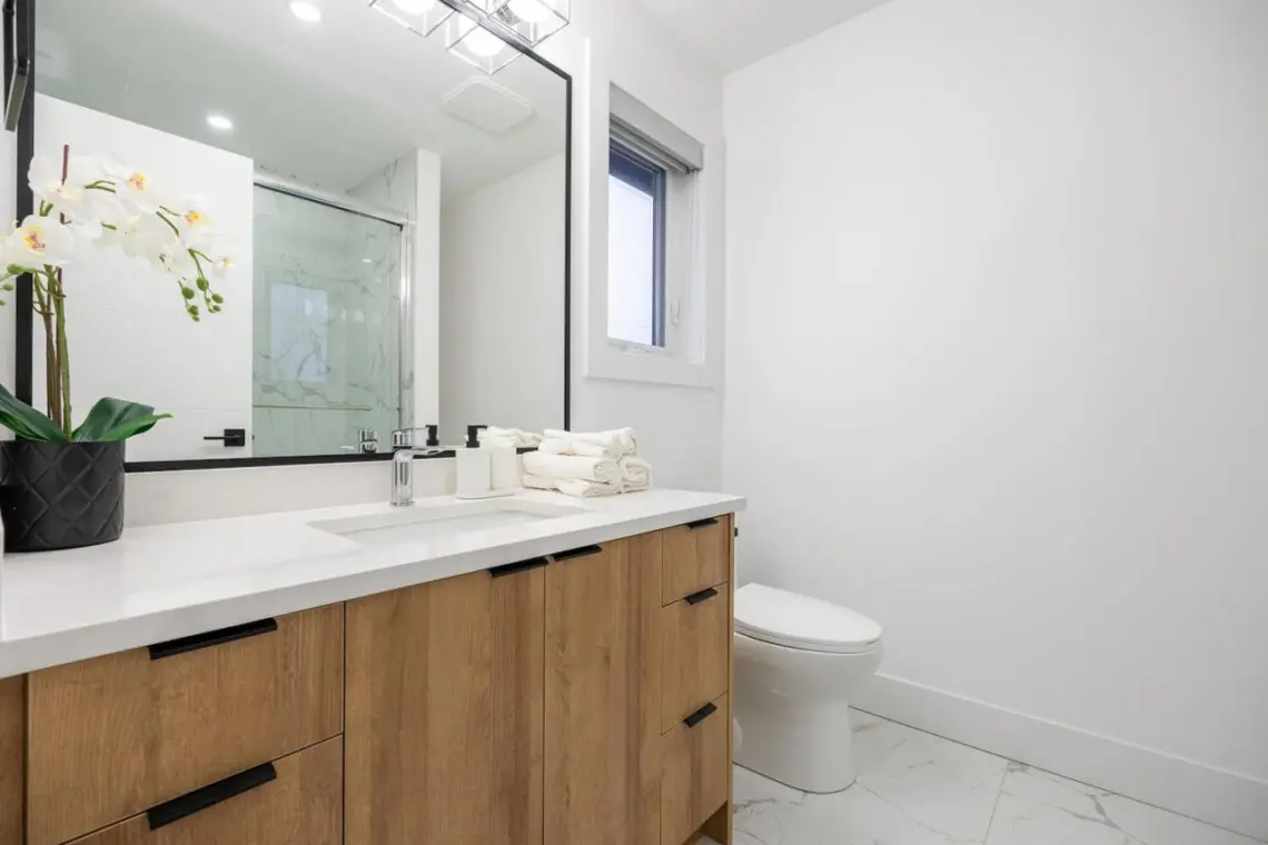 This modern ensuite bathroom features clean lines, a spacious vanity, and a refreshing glass-enclosed shower — creating a calm, spa-like retreat connected to the second bedroom for added comfort and privacy.