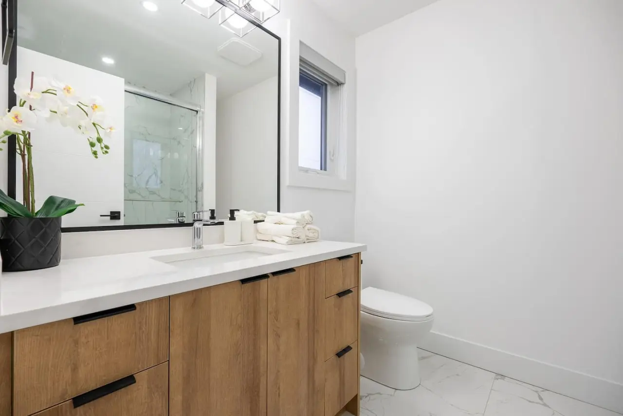 This modern ensuite bathroom features clean lines, a spacious vanity, and a refreshing glass-enclosed shower — creating a calm, spa-like retreat connected to the second bedroom for added comfort and privacy.