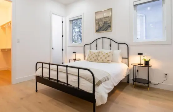 Located on the main floor, this inviting bedroom features a plush queen bed, soft lighting, and a soothing neutral palette. With its warm ambiance and modern furnishings, it offers guests a restful space to unwind and enjoy a peaceful night’s sleep.
