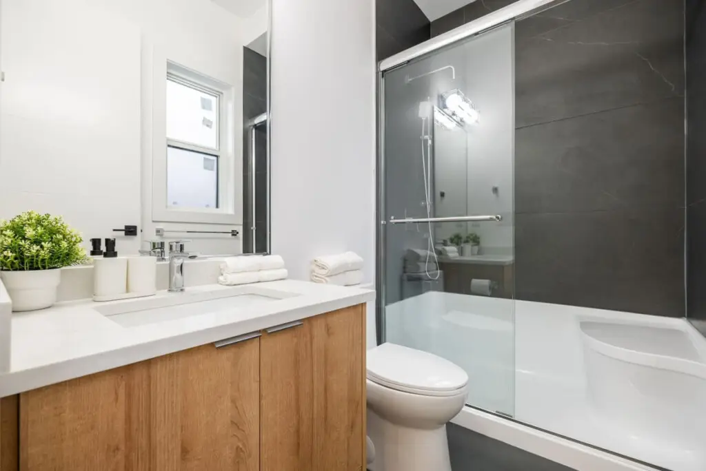 Connected to the fifth bedroom, this stylish ensuite features a glass-enclosed shower with a convenient sitting ledge, warm wood accents, and modern fixtures — a private, spa-like space to refresh and unwind.