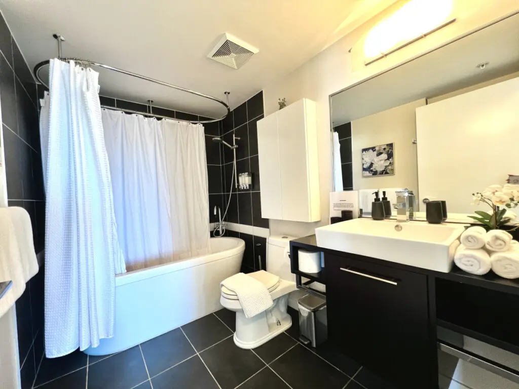 Elegant and serene, this full bathroom features a deep soaking tub, modern fixtures, and fresh towels — creating a spa-like atmosphere perfect for unwinding after a full day in the city.