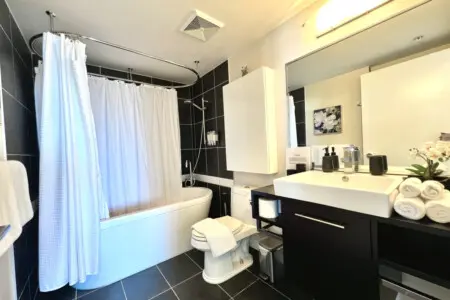 Elegant and serene, this full bathroom features a deep soaking tub, modern fixtures, and fresh towels — creating a spa-like atmosphere perfect for unwinding after a full day in the city.