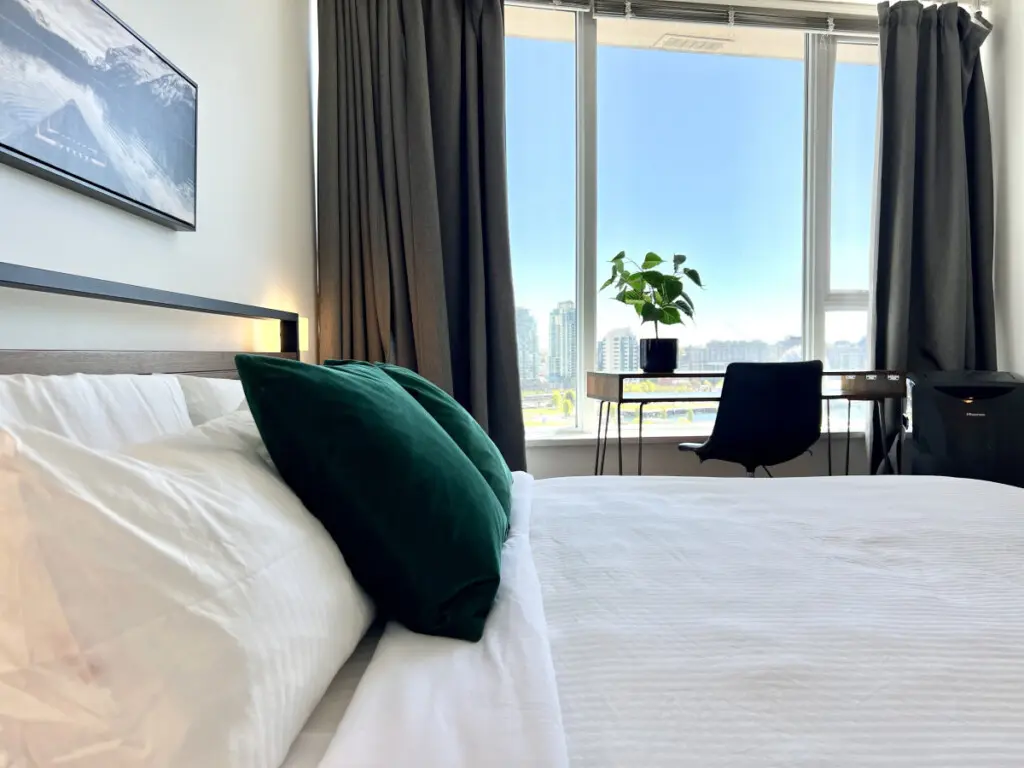 Enjoy restful nights and gentle morning light in this serene bedroom, featuring plush bedding, modern touches, and inspiring city views — a true urban retreat in Vancouver.