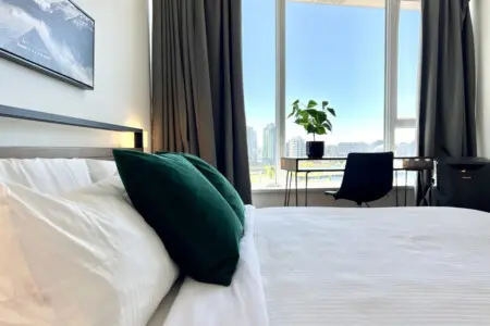 Enjoy restful nights and gentle morning light in this serene bedroom, featuring plush bedding, modern touches, and inspiring city views — a true urban retreat in Vancouver.