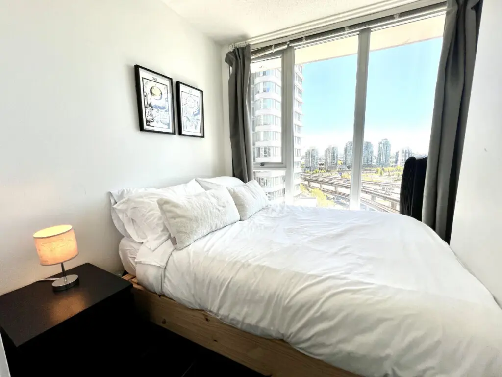 Wake up to city views and natural light in this cozy bedroom retreat, where crisp linens and soft tones create a peaceful haven for restful nights in Vancouver.