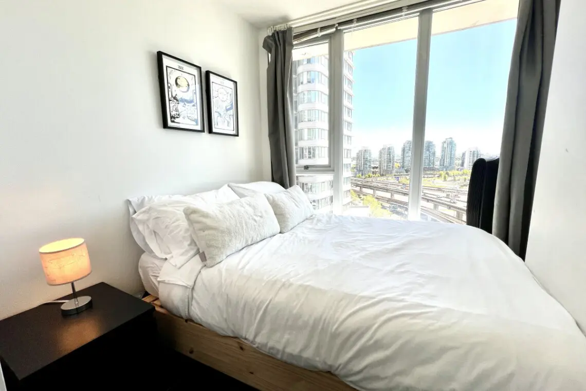 Wake up to city views and natural light in this cozy bedroom retreat, where crisp linens and soft tones create a peaceful haven for restful nights in Vancouver.