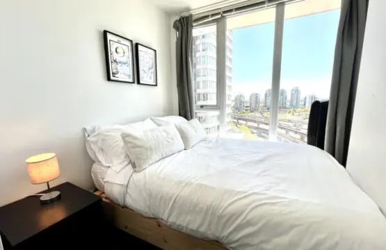 Wake up to city views and natural light in this cozy bedroom retreat, where crisp linens and soft tones create a peaceful haven for restful nights in Vancouver.