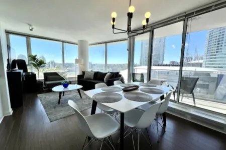 Gather for meals and conversation in this bright, open-concept living and dining area, where floor-to-ceiling windows frame stunning city and waterfront views.