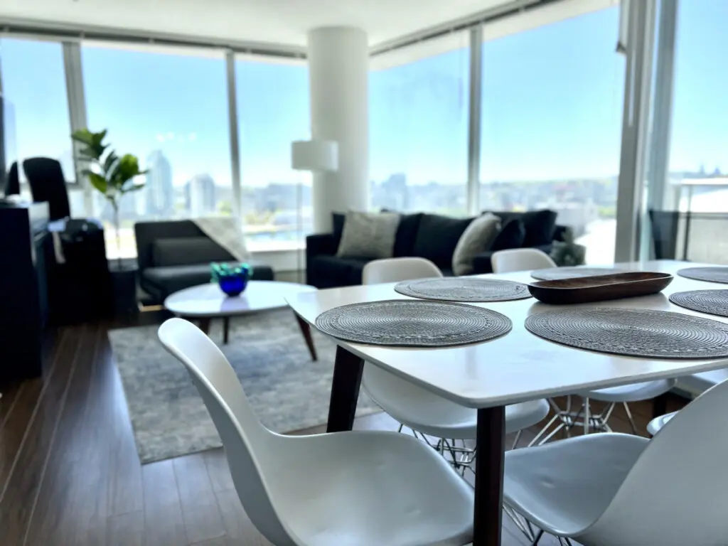 This open-concept living and dining space invites guests to gather, share meals, and unwind amid floor-to-ceiling windows and sweeping city views — the heart of your modern Vancouver escape.