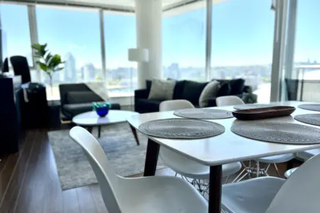 This open-concept living and dining space invites guests to gather, share meals, and unwind amid floor-to-ceiling windows and sweeping city views — the heart of your modern Vancouver escape.