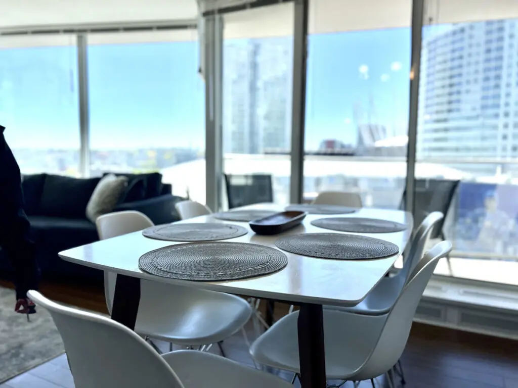 Gather for shared meals and meaningful moments at this modern dining table, surrounded by floor-to-ceiling windows and stunning city views that elevate every dining experience.