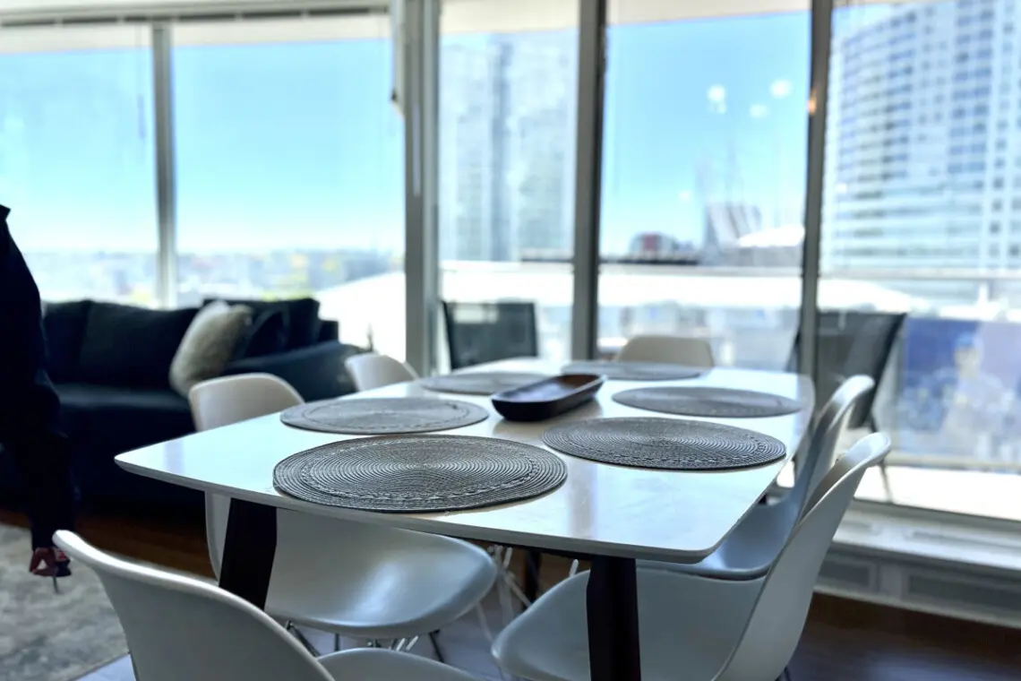 Gather for shared meals and meaningful moments at this modern dining table, surrounded by floor-to-ceiling windows and stunning city views that elevate every dining experience.