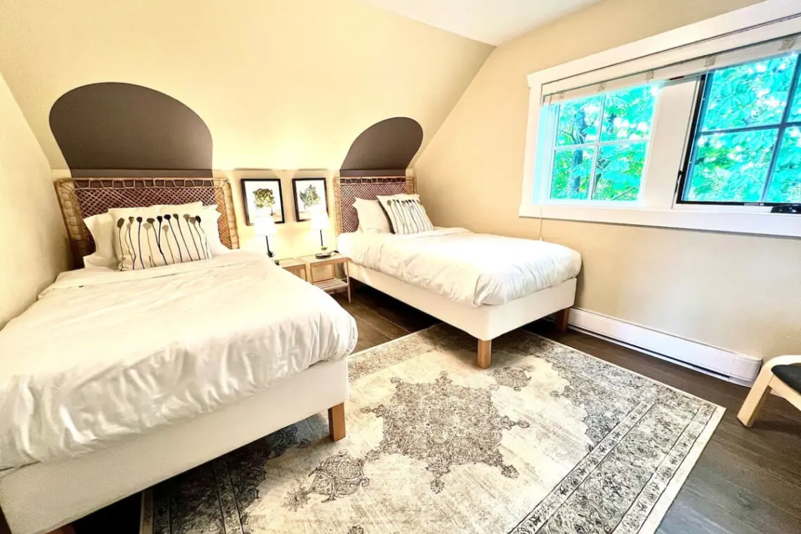 Bright and airy, this third-floor bedroom features two twin beds and calming tones — an inviting space perfect for family or friends.