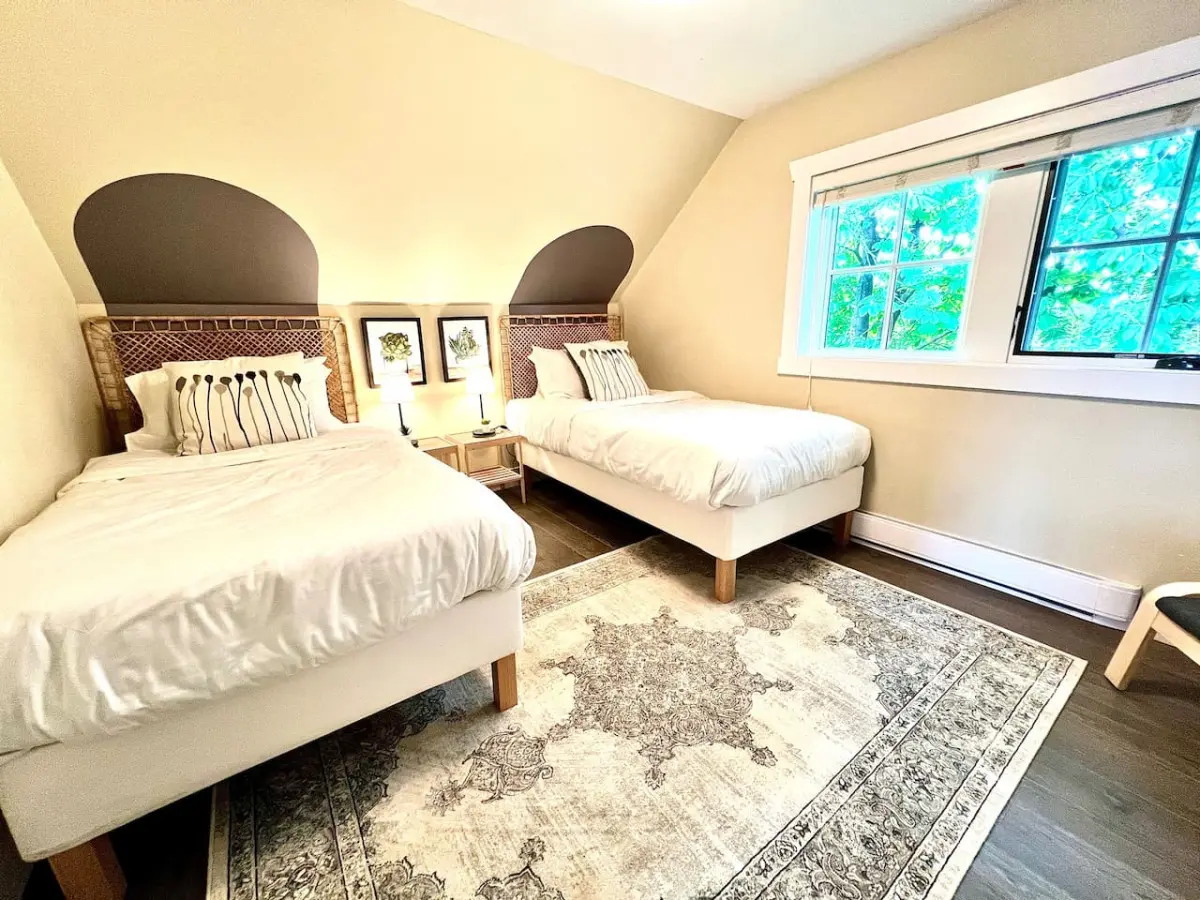 Bright and airy, this third-floor bedroom features two twin beds and calming tones — an inviting space perfect for family or friends.