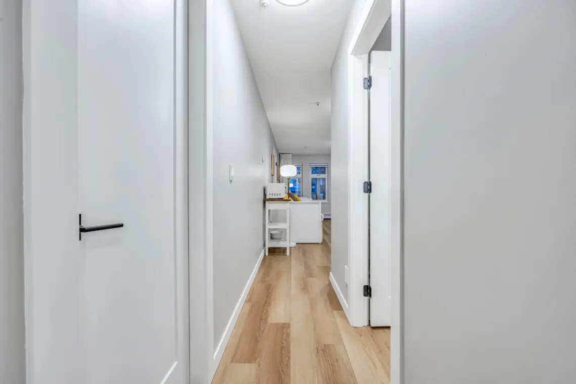 A bright hallway with sleek finishes and warm wood floors leading to the inviting living space — a seamless flow that enhances the home’s modern, open feel.