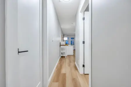 A bright hallway with sleek finishes and warm wood floors leading to the inviting living space — a seamless flow that enhances the home’s modern, open feel.