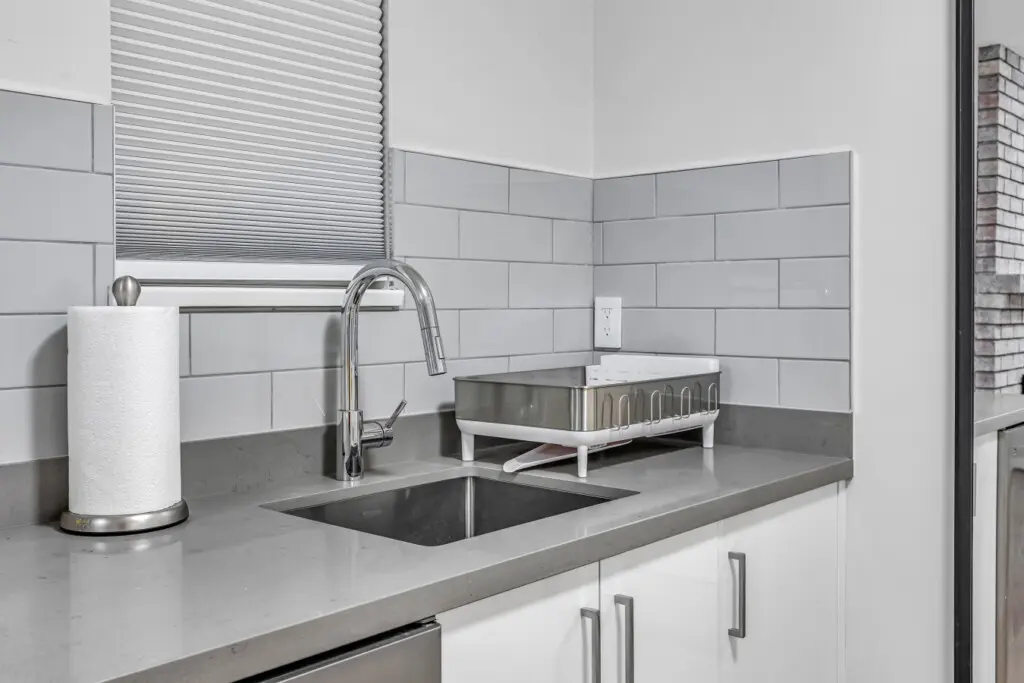 A thoughtfully designed kitchenette featuring a sleek sink, dishwasher, and modern finishes. Guests can easily prepare light meals, enjoy a quiet coffee, or unwind with home-style comfort right in their own private space.