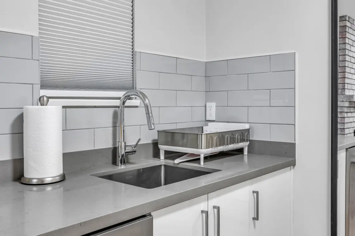 A thoughtfully designed kitchenette featuring a sleek sink, dishwasher, and modern finishes. Guests can easily prepare light meals, enjoy a quiet coffee, or unwind with home-style comfort right in their own private space.