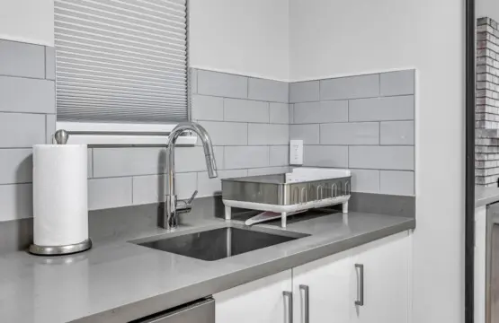 A thoughtfully designed kitchenette featuring a sleek sink, dishwasher, and modern finishes. Guests can easily prepare light meals, enjoy a quiet coffee, or unwind with home-style comfort right in their own private space.