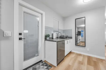 A bright, modern kitchenette featuring sleek cabinetry, stainless steel accents, and warm wood flooring — the perfect spot to enjoy simple meals and cozy moments during your stay.
