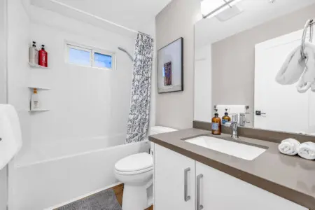 A sleek and modern bathroom featuring a relaxing bathtub, fresh linens, and thoughtful amenities for a refreshing stay.