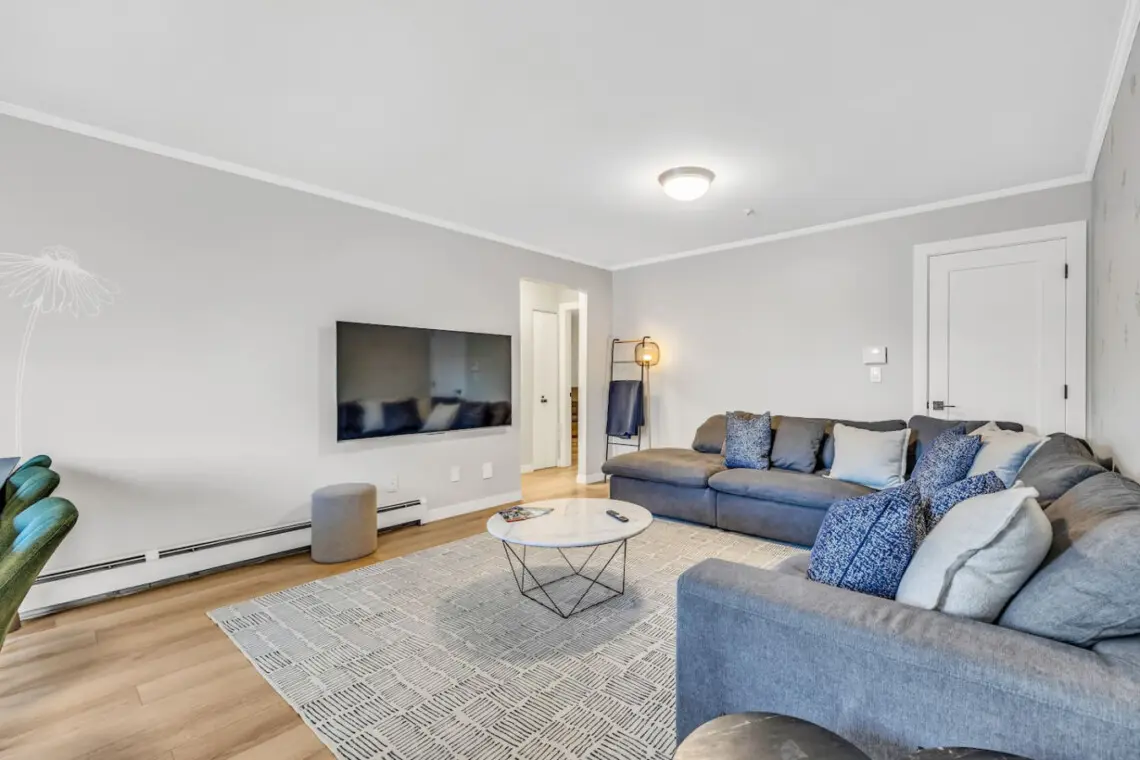A spacious and comfortable living room designed for relaxation, featuring a large sectional sofa, cozy lighting, and a smart TV — the perfect spot to unwind or enjoy movie nights after a day of exploring.