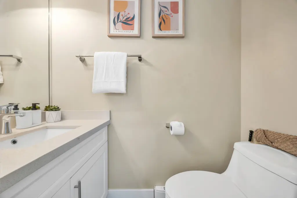 Powder bathroom on the 1st floor equipped with a clean sink, mirror, and toilet for your comfort.