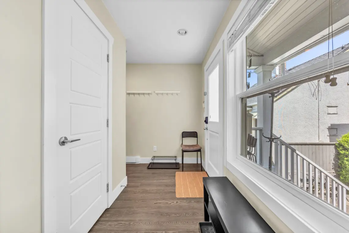 Bright and airy hallway offering a warm welcome upon entry, complete with convenient seating, coat hooks, and natural light streaming through large windows — a functional yet inviting transition into the home’s cozy living spaces.