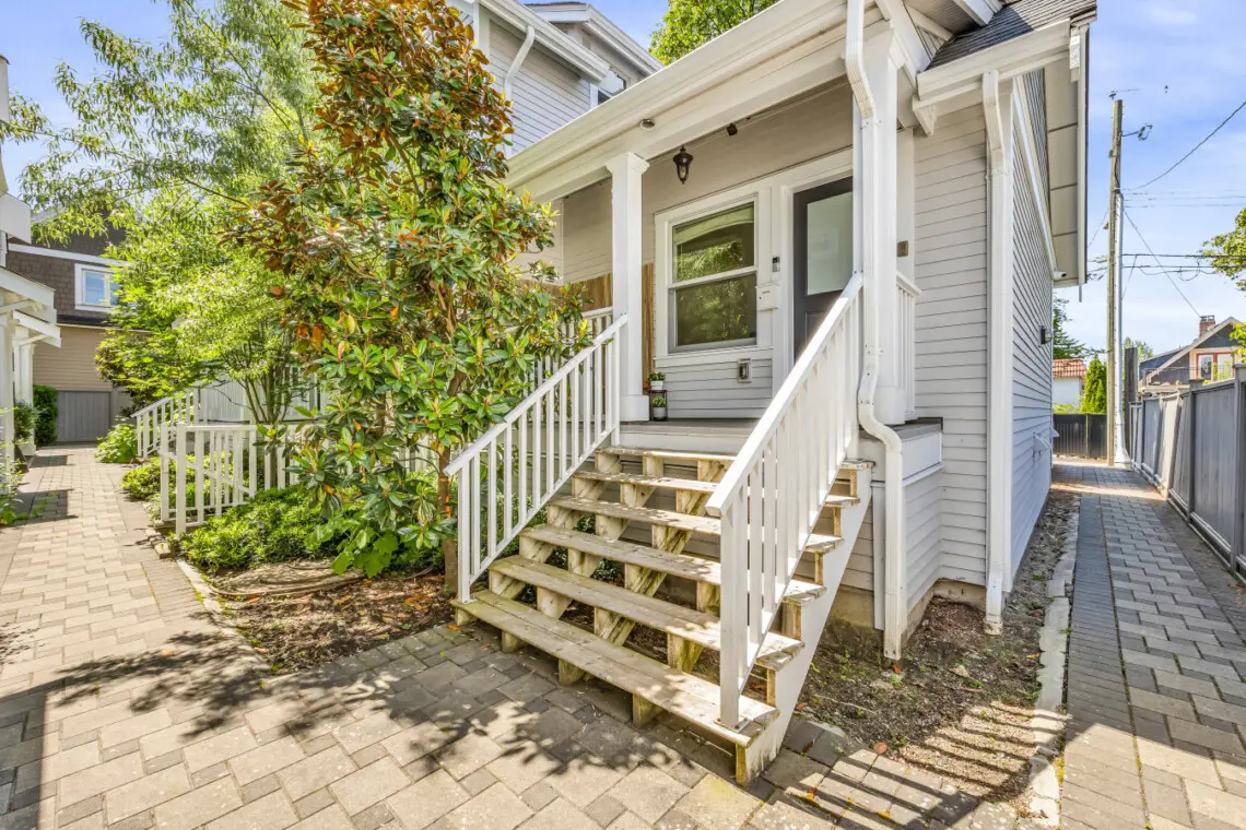 Charming front entrance surrounded by lush greenery, welcoming guests with a warm and inviting pathway leading up to the home’s cozy porch.