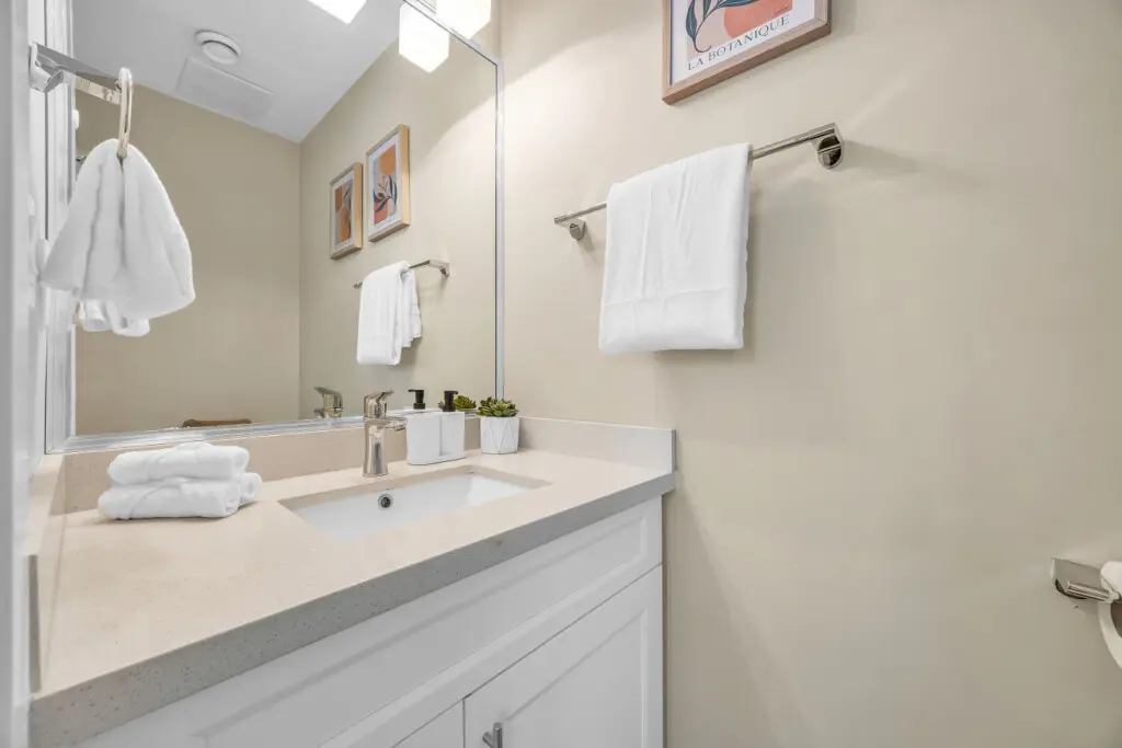 Powder bathroom on the first floor, off of the main hallway near the living room - equipped with a clean sink, mirror, and toilet for your comfort.