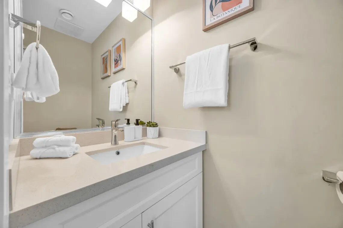 Powder bathroom on the first floor, off of the main hallway near the living room - equipped with a clean sink, mirror, and toilet for your comfort.