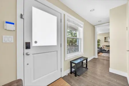 Bright and welcoming hallway that greets guests upon entry, featuring warm tones, natural light, and a clean, modern design that leads seamlessly into the inviting living area.