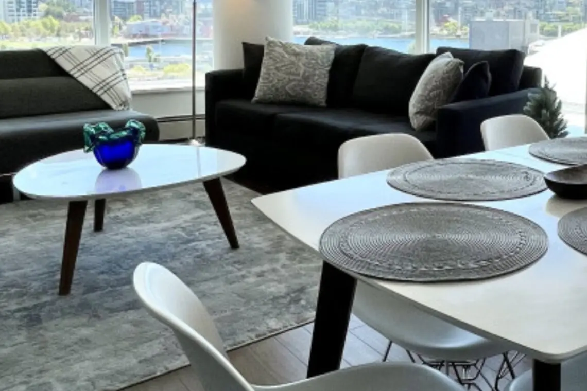 This open-concept living and dining space invites guests to gather, share meals, and unwind amid floor-to-ceiling windows and sweeping city views — the heart of your modern Vancouver escape.