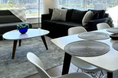 This open-concept living and dining space invites guests to gather, share meals, and unwind amid floor-to-ceiling windows and sweeping city views — the heart of your modern Vancouver escape.