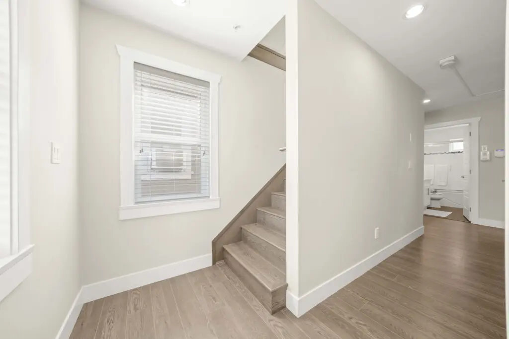 A bright landing area leads to the staircase up to the third floor, where guests will find additional living space and comfort. Clean lines and natural light enhance the home’s open, welcoming feel.