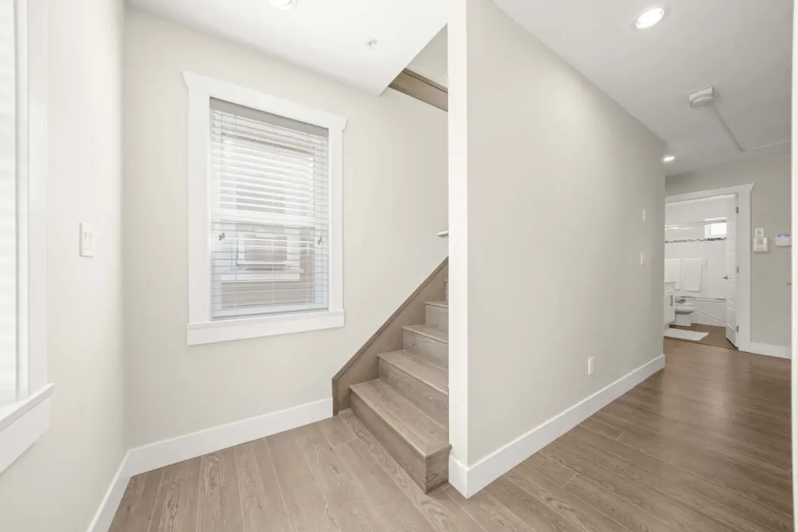 A bright landing area leads to the staircase up to the third floor, where guests will find additional living space and comfort. Clean lines and natural light enhance the home’s open, welcoming feel.